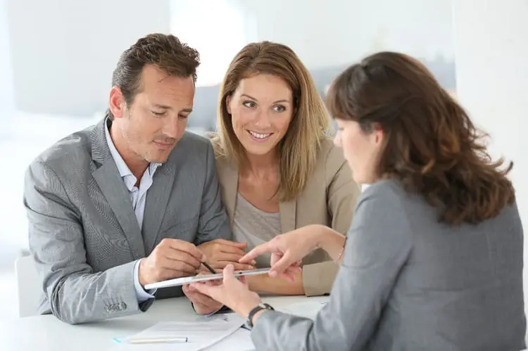 A couple and an insurance agent reviewing paperwork at a table