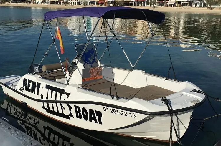 A small rental boat with a canopy moored by a dock